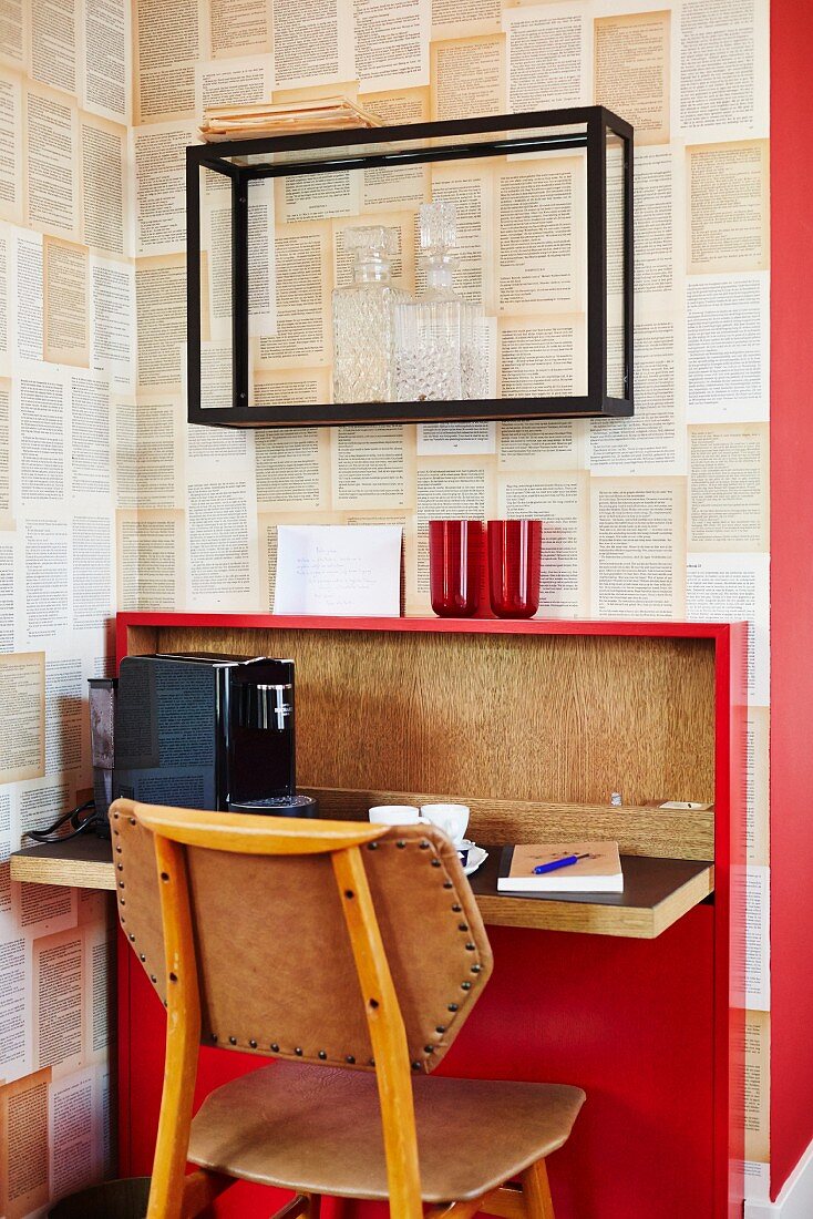 Stuhl vor kleinem Schreibtisch in Rot mit klappbarer Platte an Wand mit Designertapete