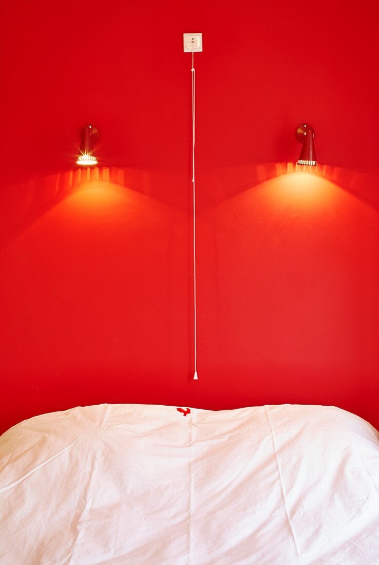 Bett vor roter Wand mit Beleuchtung