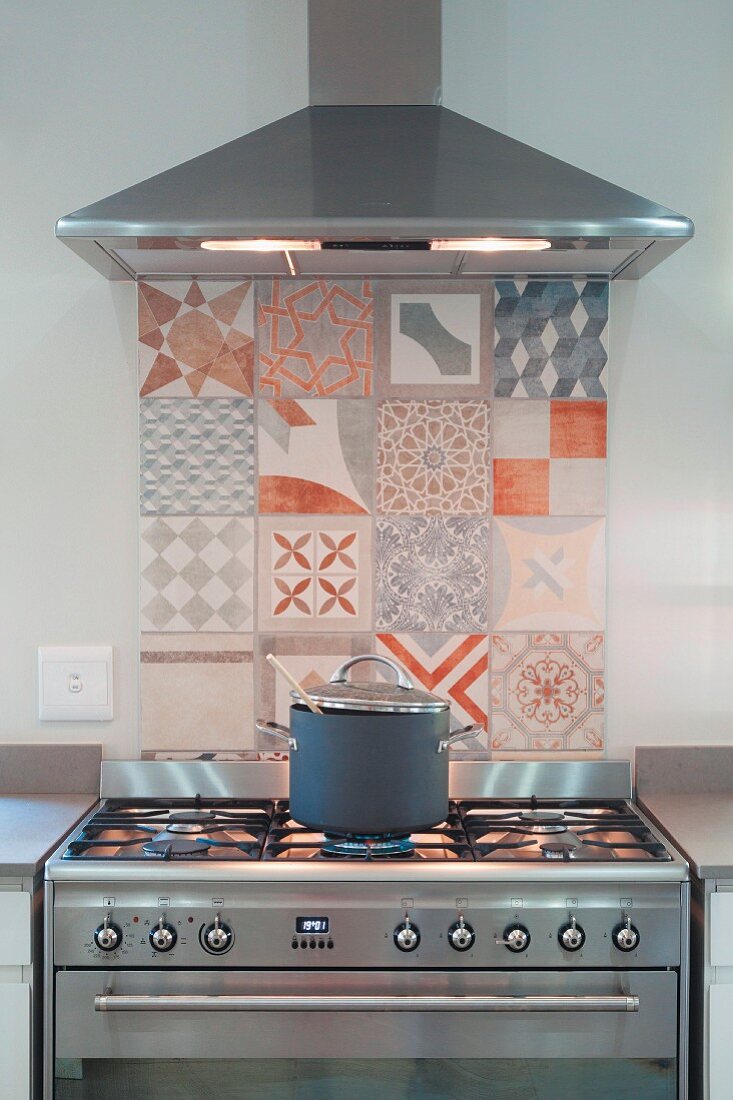 Splashback made from painted tiles with various patterns behind gas cooker