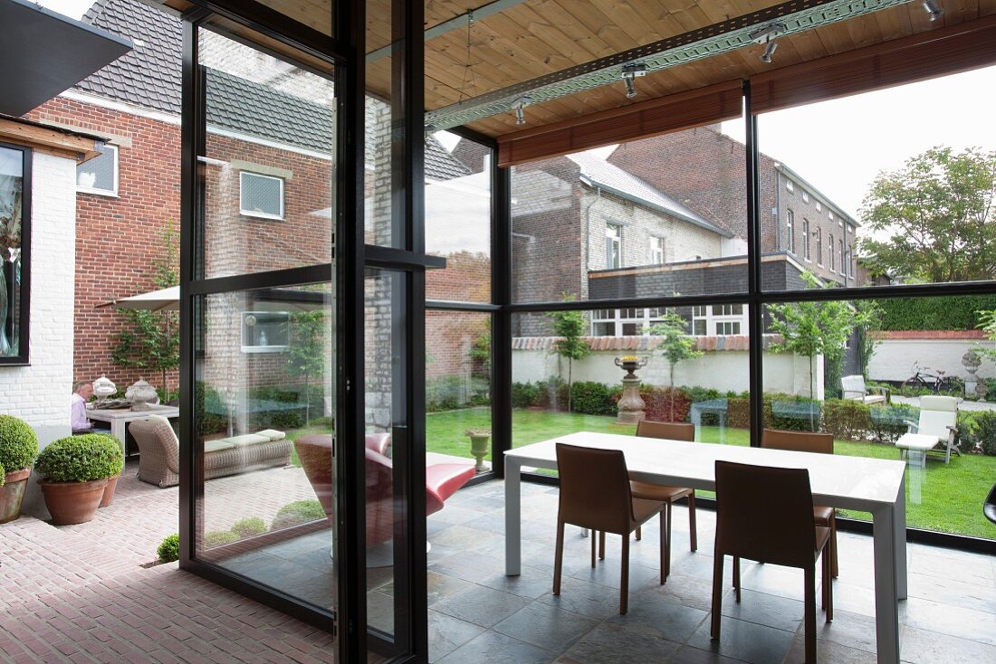 View into modern glass extension with dining area and view of garden