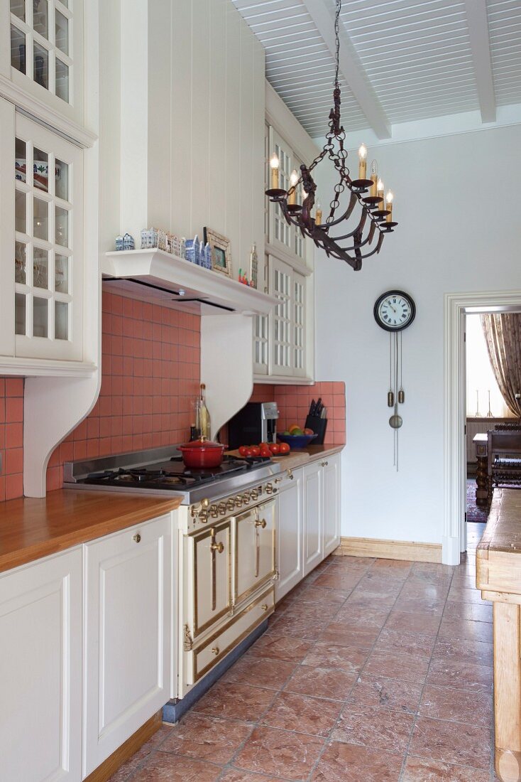 Küchenzeile mit weissen Unterschränken in elegantem Landhausstil und Decken- Kerzenleuchter an weißer Holzdecke