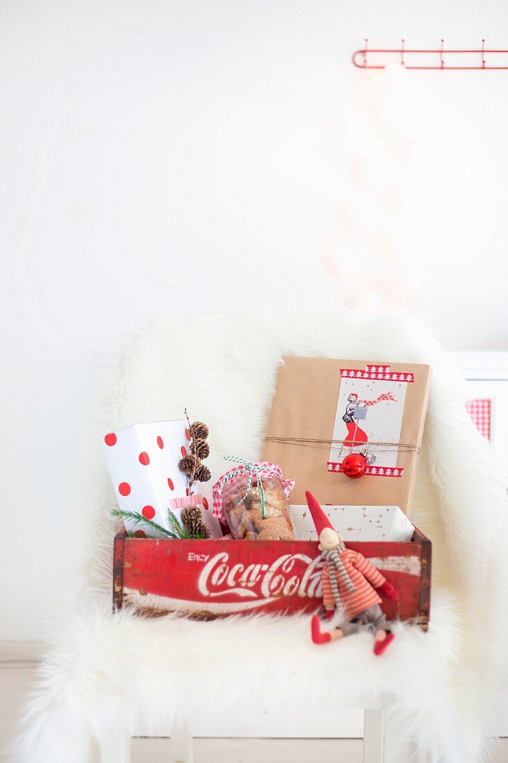 Beschriftete Holzkiste mit Weihnachtswichtel und verpackten Geschenken
