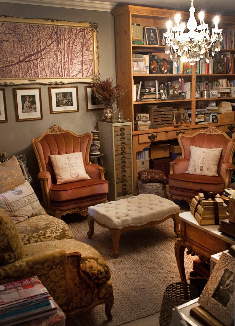 Sitzgruppe mit Sofa und Sesseln in antikem Stil um Polstertisch unter Kronleuchter in Wohnzimmer