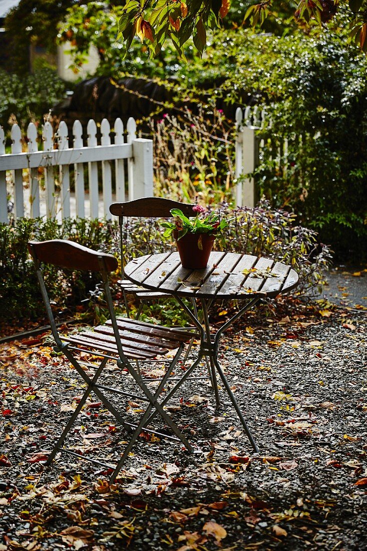 Kleiner Tisch mit Stühlen in herbstlichem Garten