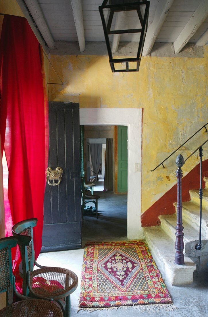 Rustic stairwell with open, black-painted front door