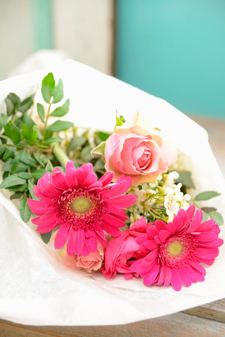 Blumenstrauß aus Rosen, Gerberas und Wachsblumen in Seidenpapier gewickelt
