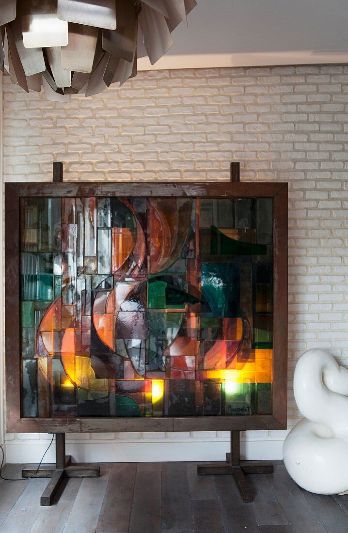 Hinterleuchtete Glaskunst vor weisser Ziegelwand aufgestellt