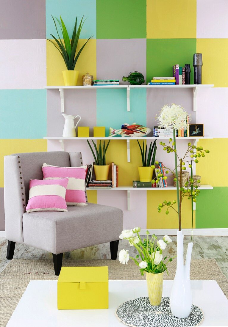 Frühlingshafte Wandgestaltung mit pastellfarbenen und gelben Farbquadraten, weiße Konsolenregale mit Zimmerpflanzen