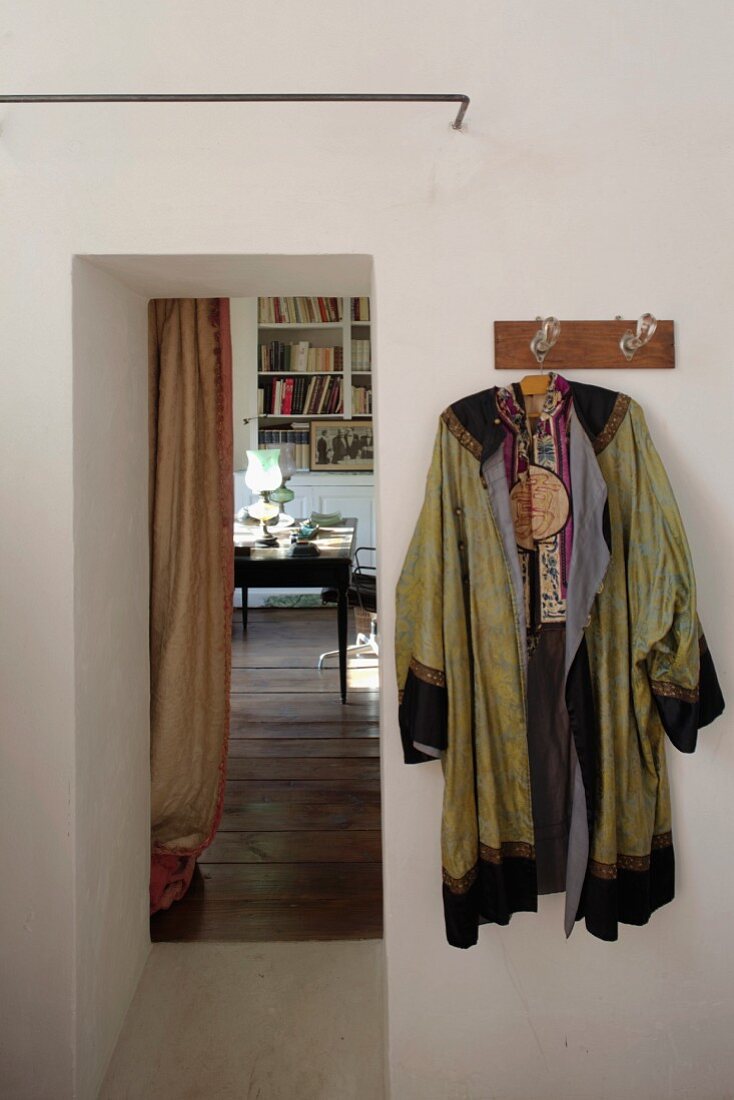 Auf Wandhakenleiste gehängter Kimono neben offenem Durchgang