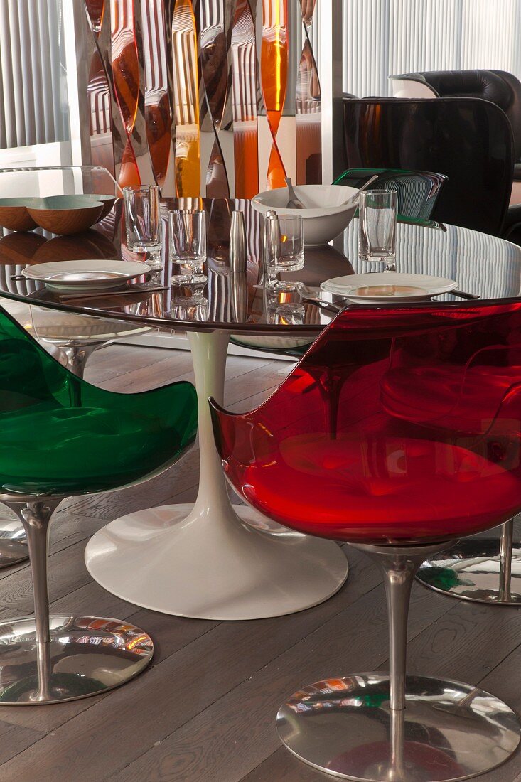 Retro-Schalenstühle aus farbigem, transparentem Kunststoff um gedeckten Tulip-Tisch