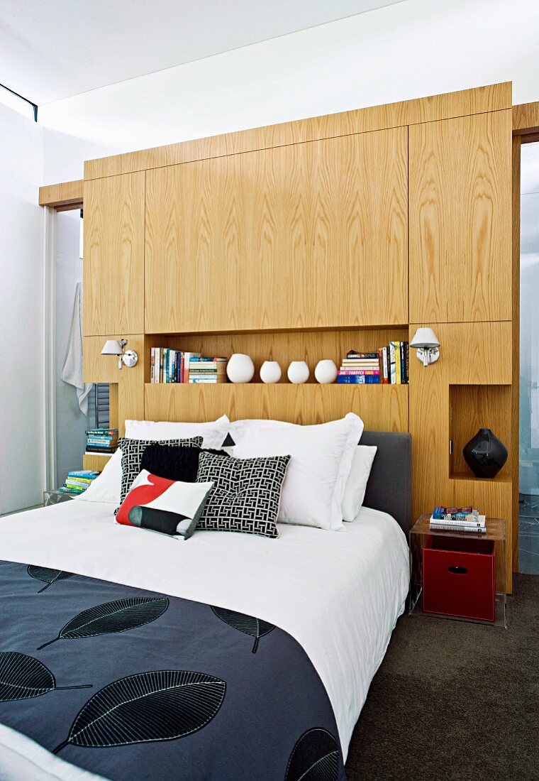 Schlafzimmer mit Doppelbett und elegante Tagesdecke mit Blattmuster, an Kopfende massgefertigter Raumteiler aus Holz