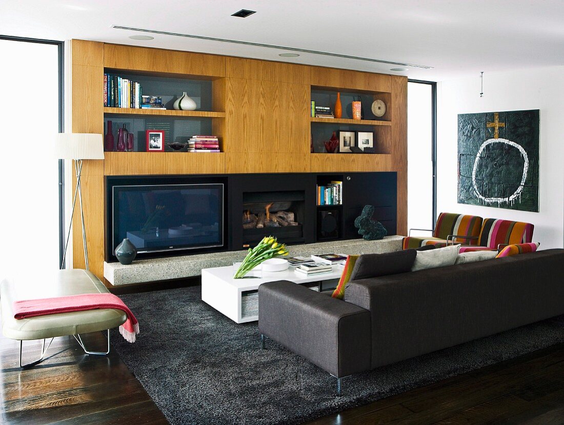 Wohnzimmer mit dunklem Sofa und Bodentisch vor massgefertigtem Wandschrank aus Holz