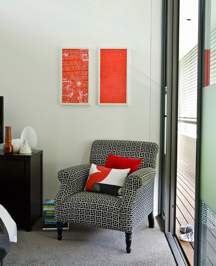 Vintage Sessel mit schwarz-weiss gemustertem Bezug vor Wand mit modernen Bildern