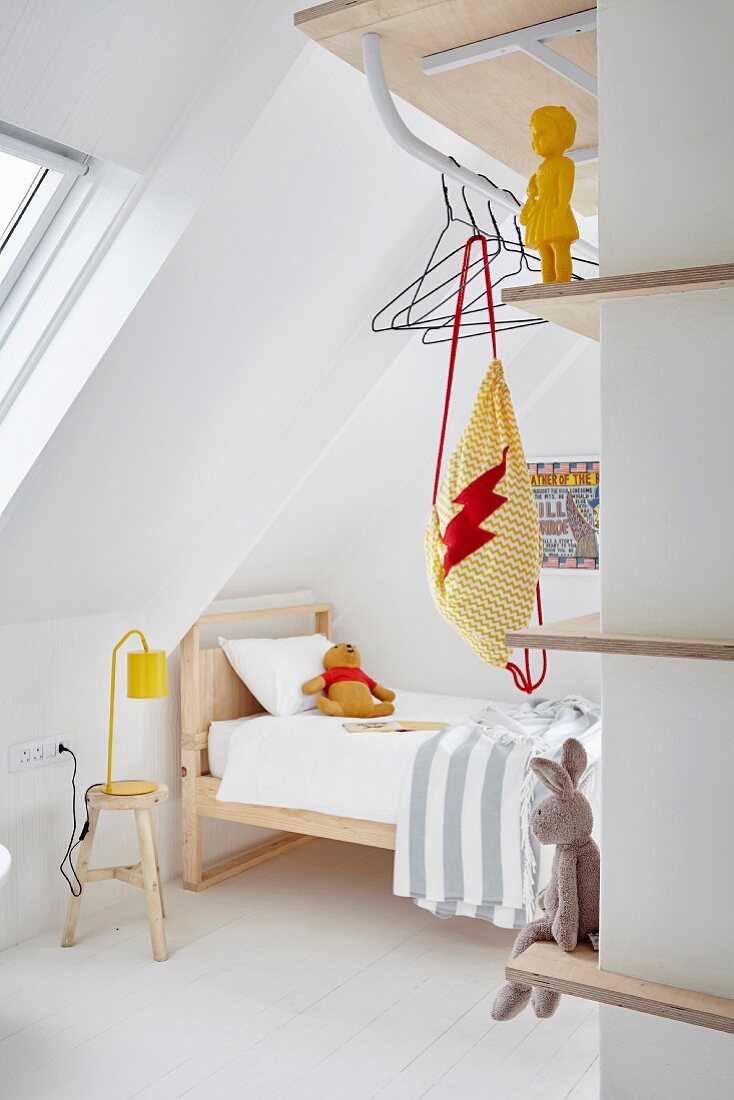 Blick in minimalistisches Kinderzimmer mit Holzbett und Kleiderstange an Regalbrett