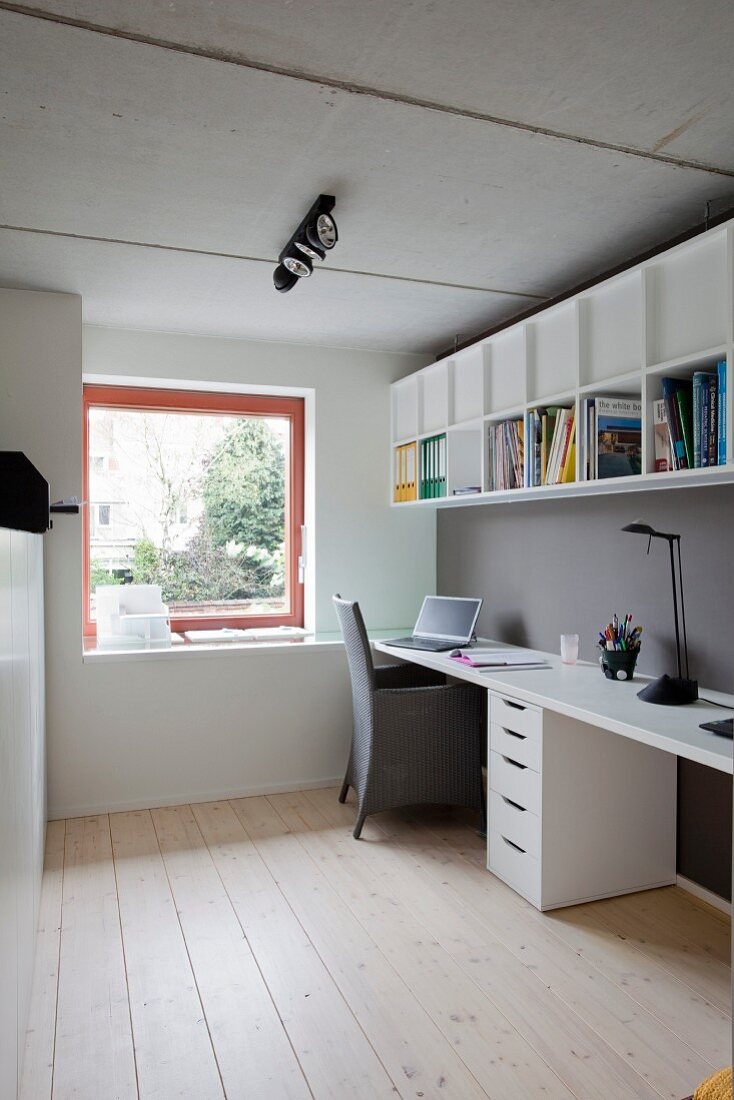 Narrow study with pale wooden floor, white desk, filing cabinet and shelves mounted on grey-painted wall