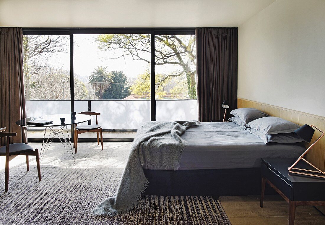 Classic designer furniture and glass wall in masculine bedroom
