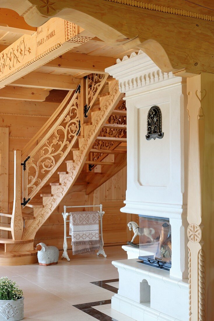 Blick auf massgefertigte Treppe mit geschnitztem Geländer und Kaminofen in einem Massivholzhaus