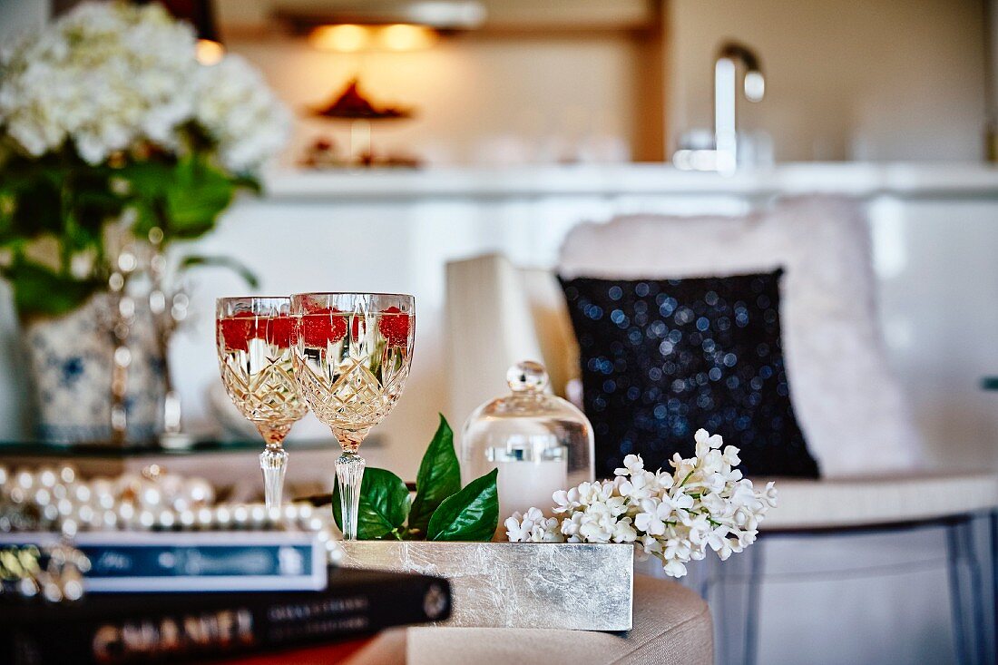 Weißwein mit Himbeeren in Kristallgläsern in elegantem Wohnraum