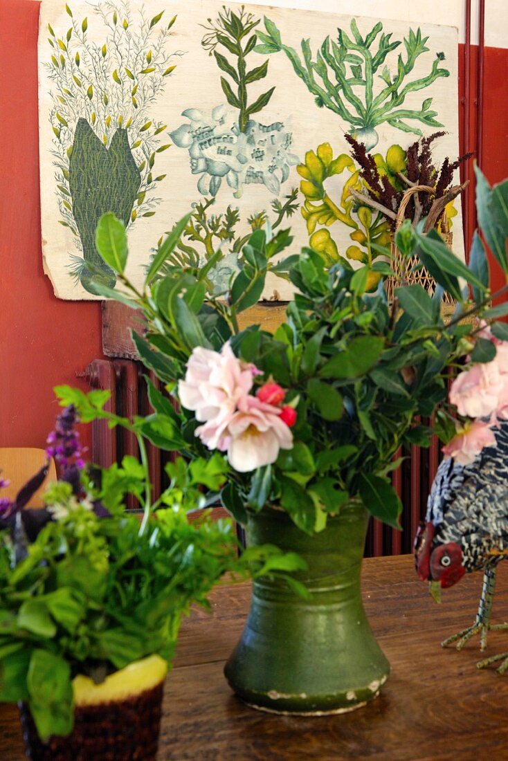 Green vase of flowers on table in front of vintage botanical illustration