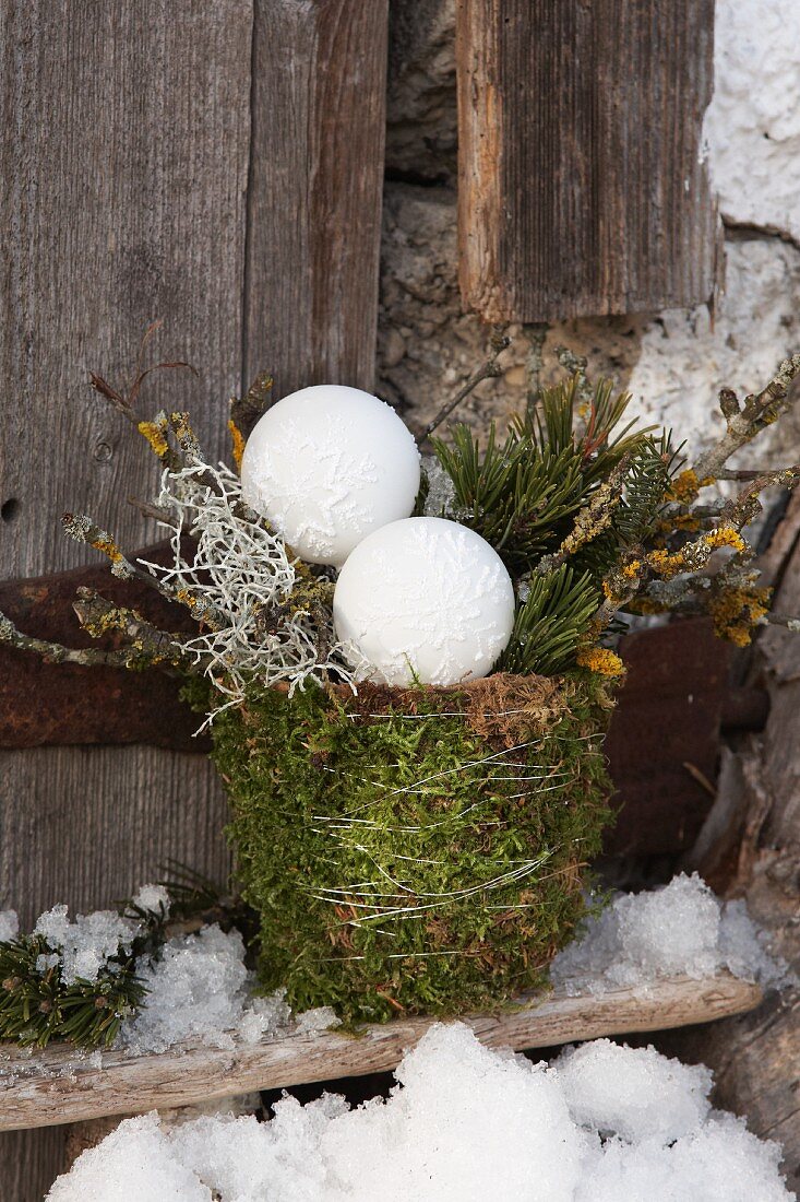 Twigs and Christmas baubles in plant pot wrapped in moss