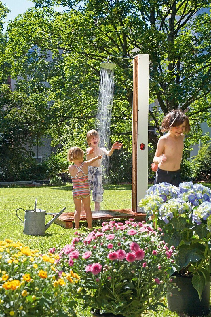 Children playing under outdoor shower in garden