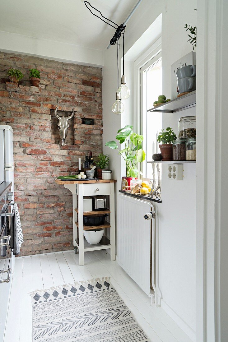 Brick wall and serving trolley in narrow kitchen