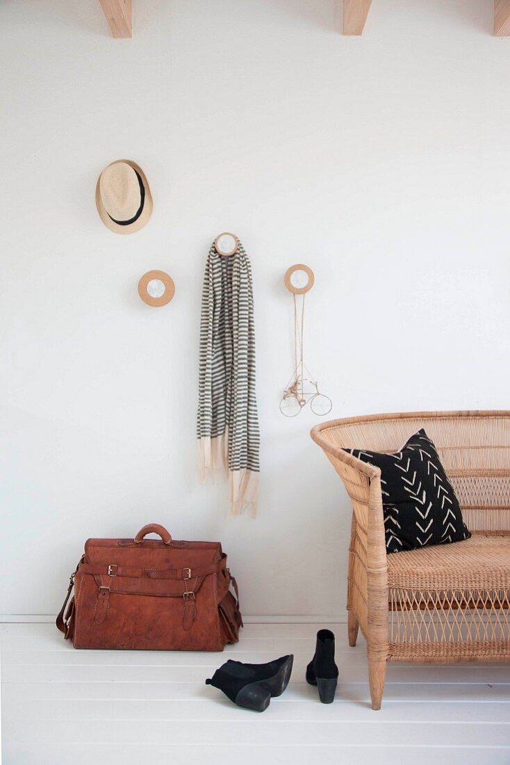 Garderobe mit runden Holzscheiben, Ledertasche und Korbsofa