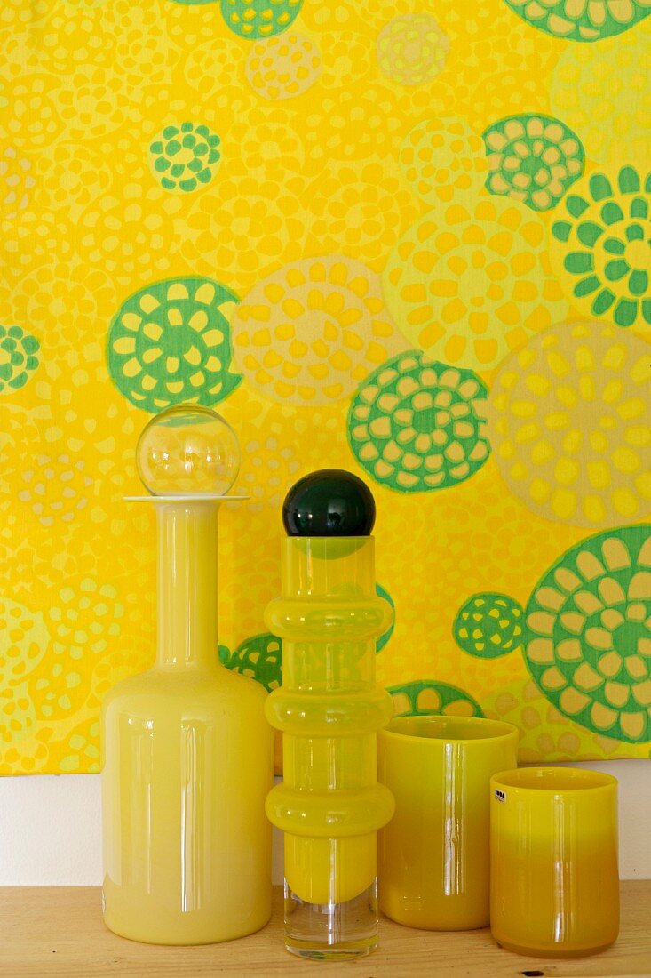 Yellow glass vases in front of yellow artworks with motif of circles
