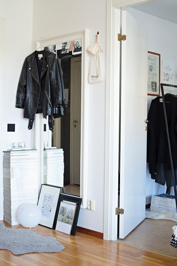 Black leather jacket hung on full-length mirror in hallway next to open interior door
