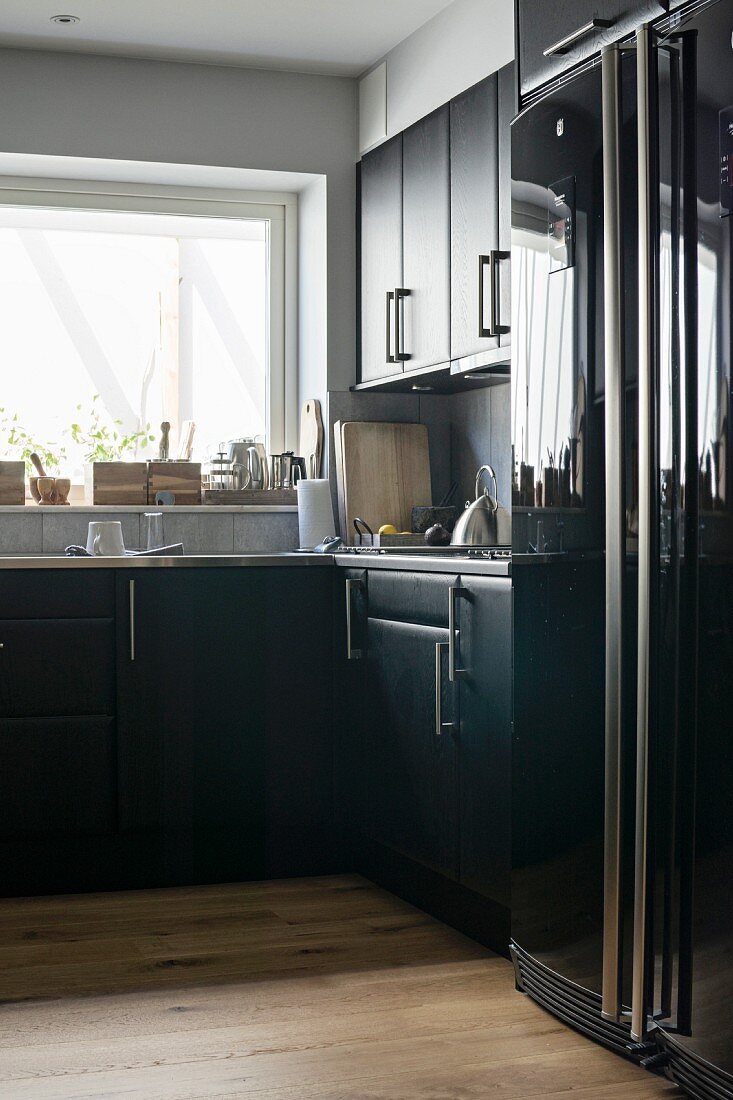 Küchenecke mit schwarzen Schränken, Kühlschrankkombination mit Hochglanzfront