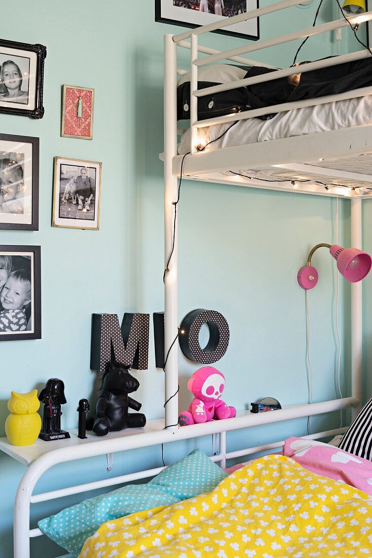 White metal bunk beds, decorative letters and framed photos of children on pale blue wall