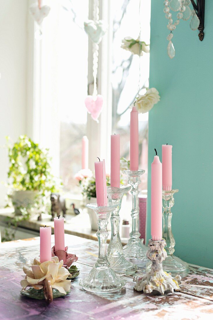 Romantische Kerzenhalter mit rosa Kerzen auf Tisch vor Fenster