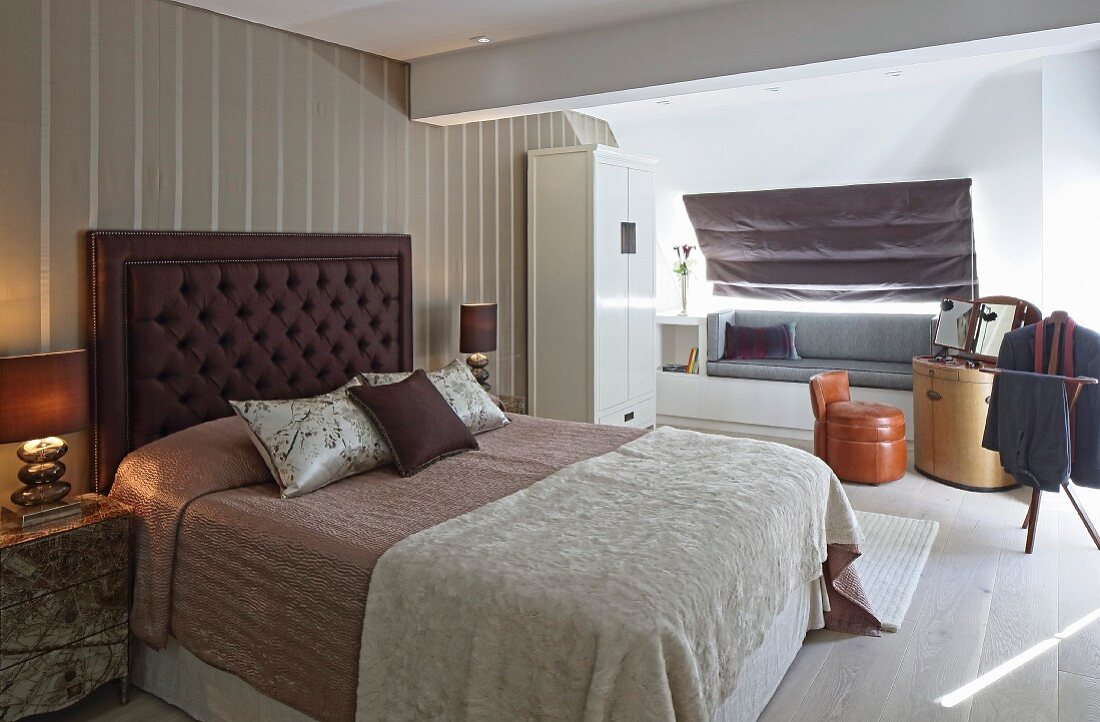 Doppelbett mit gepolstertem Kopfteil vor Streifentapete in elegantem Schlafzimmer