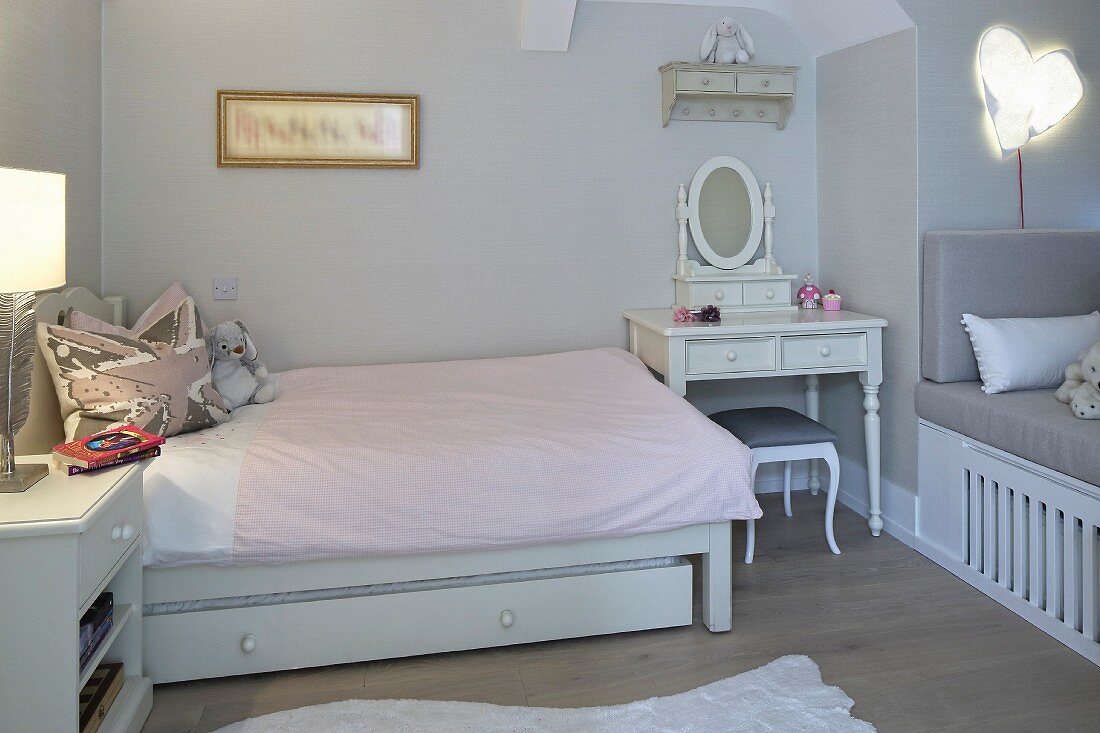 Mädchenzimmer mit romantischem Schminktisch neben Bett mit zartrosa Bettwäsche