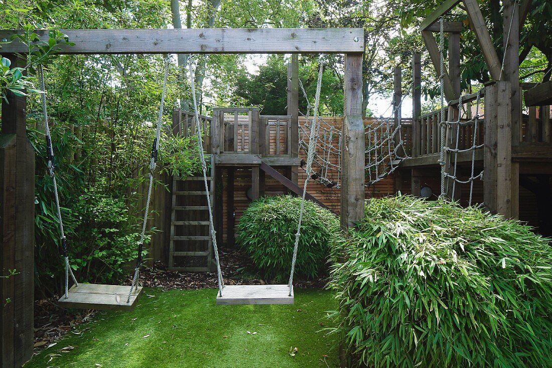 Wooden swings and climbing frame in summery garden