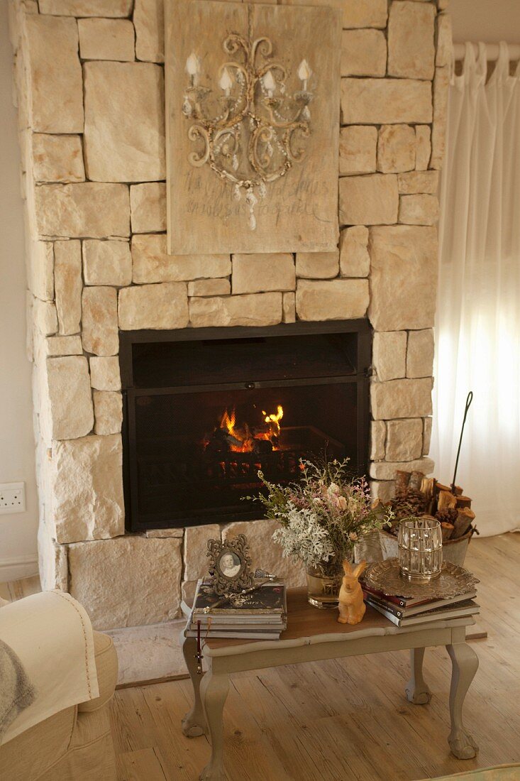 Ornaments on vintage wooden footstool in front of fire in stone fireplace