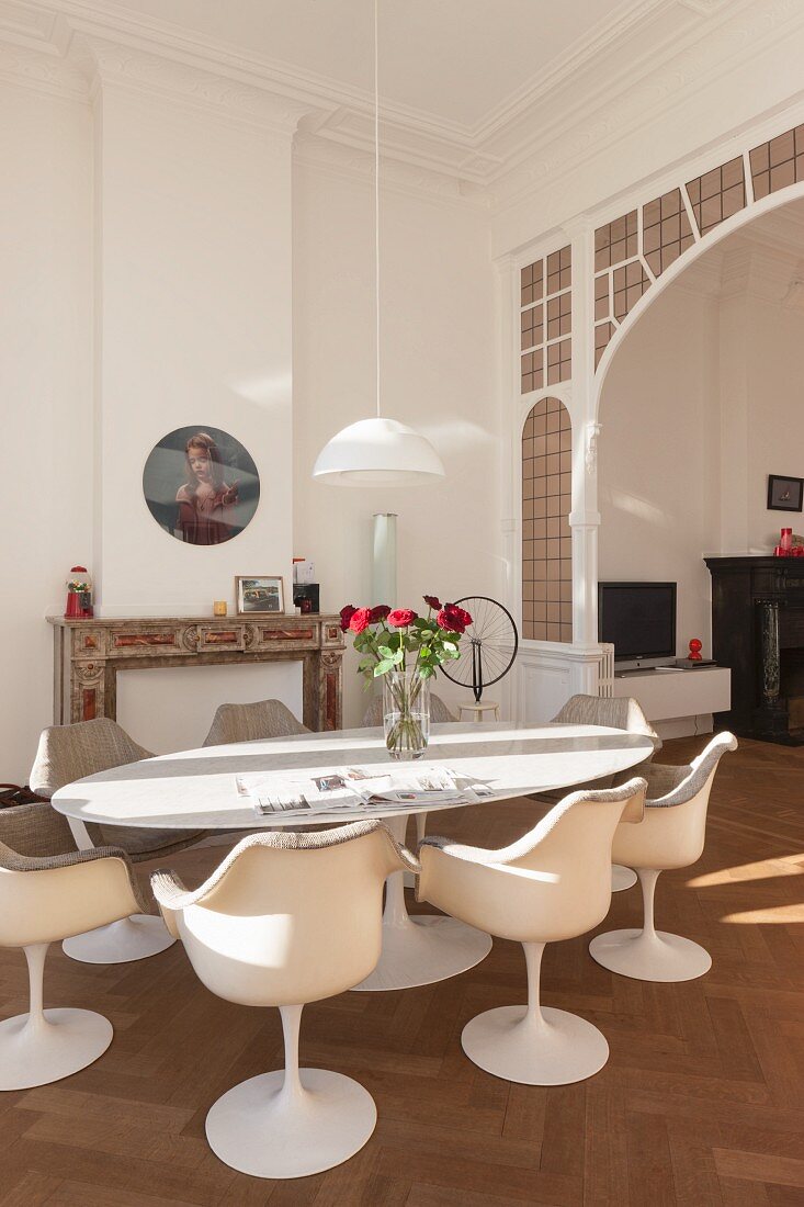 Tulip Armlehnstühle um ovalen Tisch mit Rosenstrauss, im Hintergrund traditioneller Rundbogen-Durchgang mit Bleiverglasung