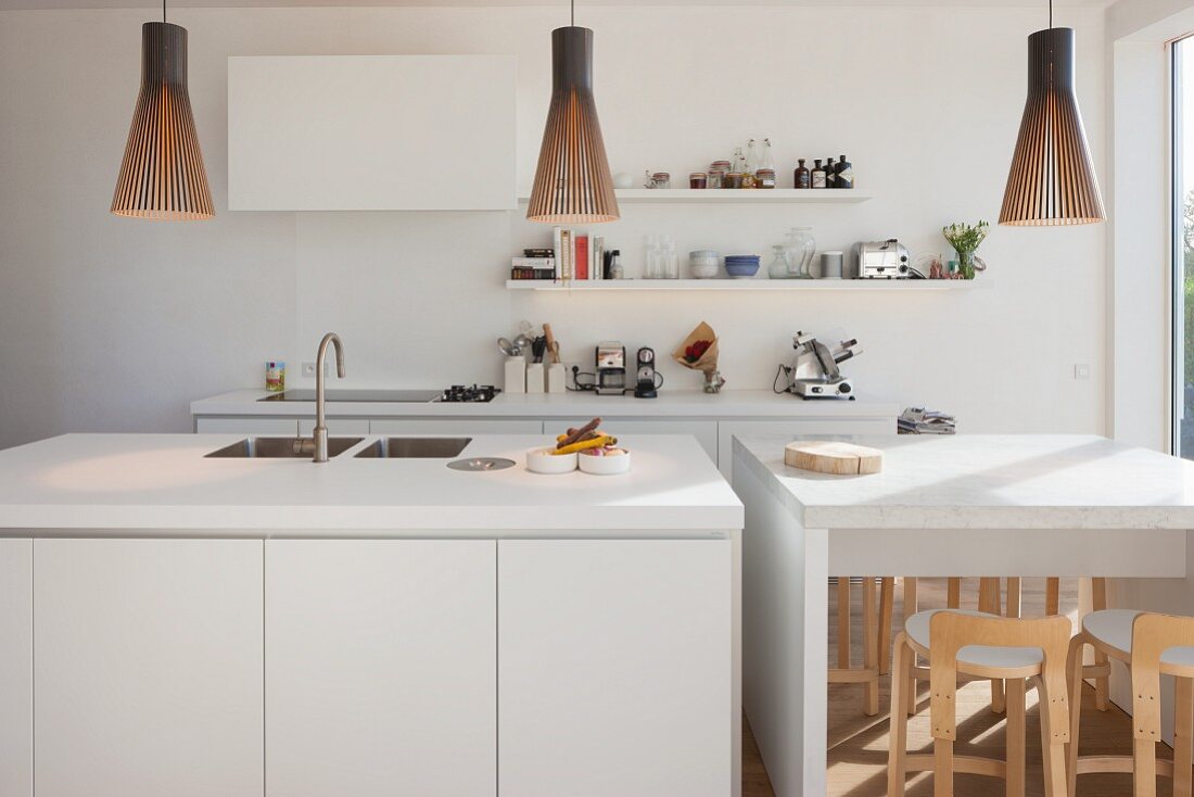 Weisser Küchenblock und Frühstückstheke mit Pendelleuchten in offener Küche