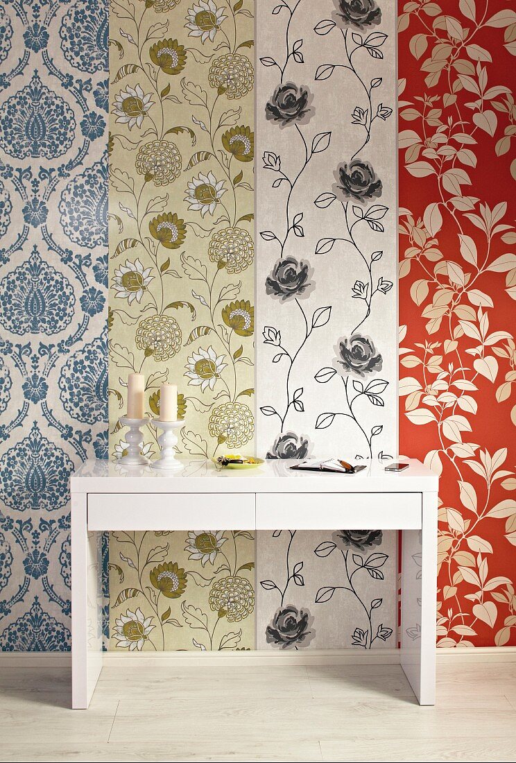 White modern console table against wall covered in mixture of patterned wallpapers