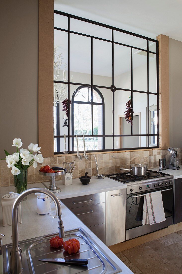 Küchenzeile übereck mit Edelstahlfronten und Innenfenster mit schwarzem Metallrahmen