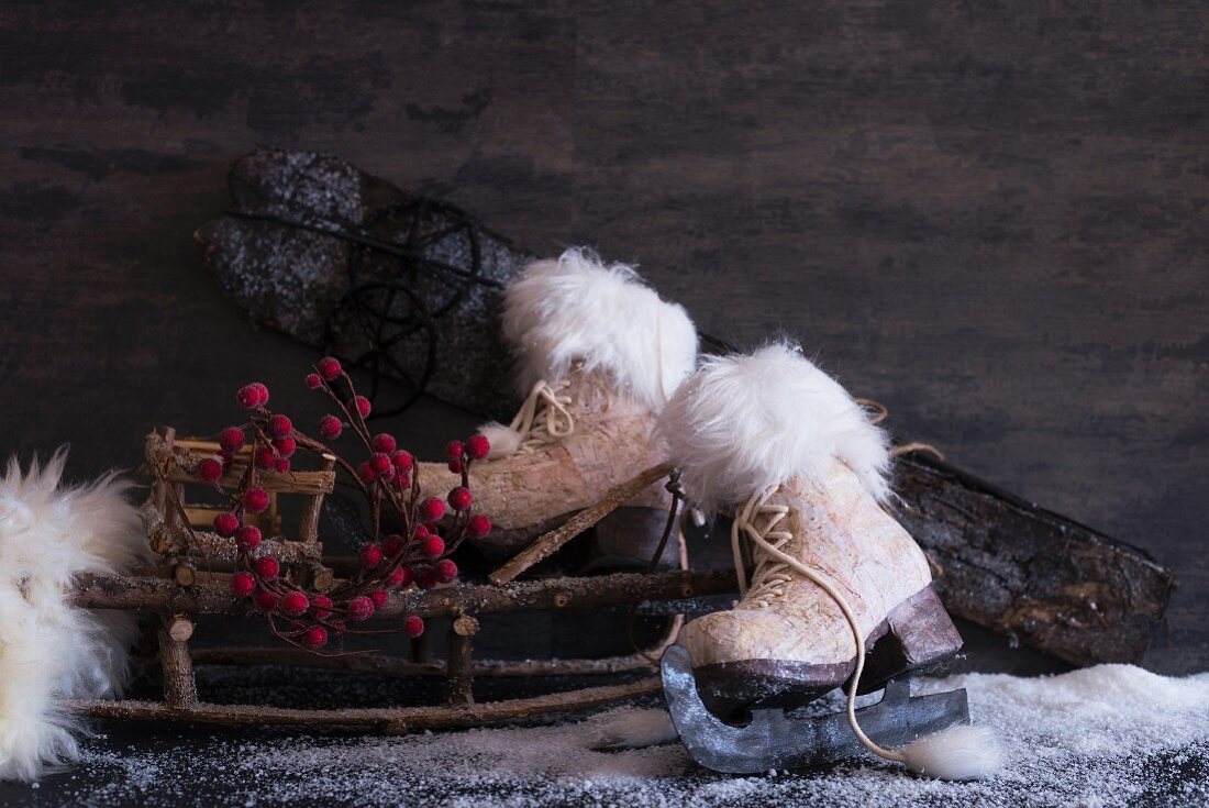 Winter still-life arrangement of old ice skates, sledge made of branches and artificial snow