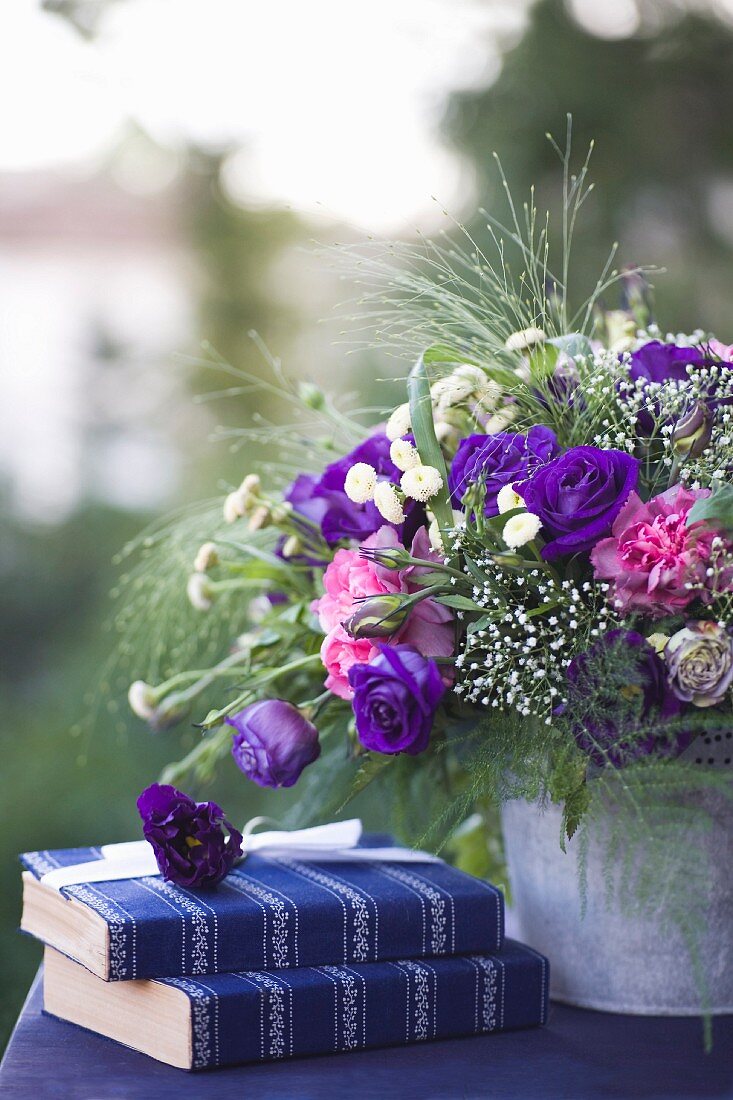 Blumenbouquet mit violetten Rosen auf Tisch im Freien