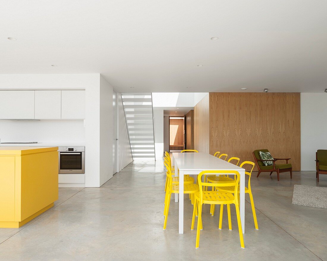 Minimalistischer Wohnraum mit Betonboden, Küche und Essbereich in Gelb & Weiß