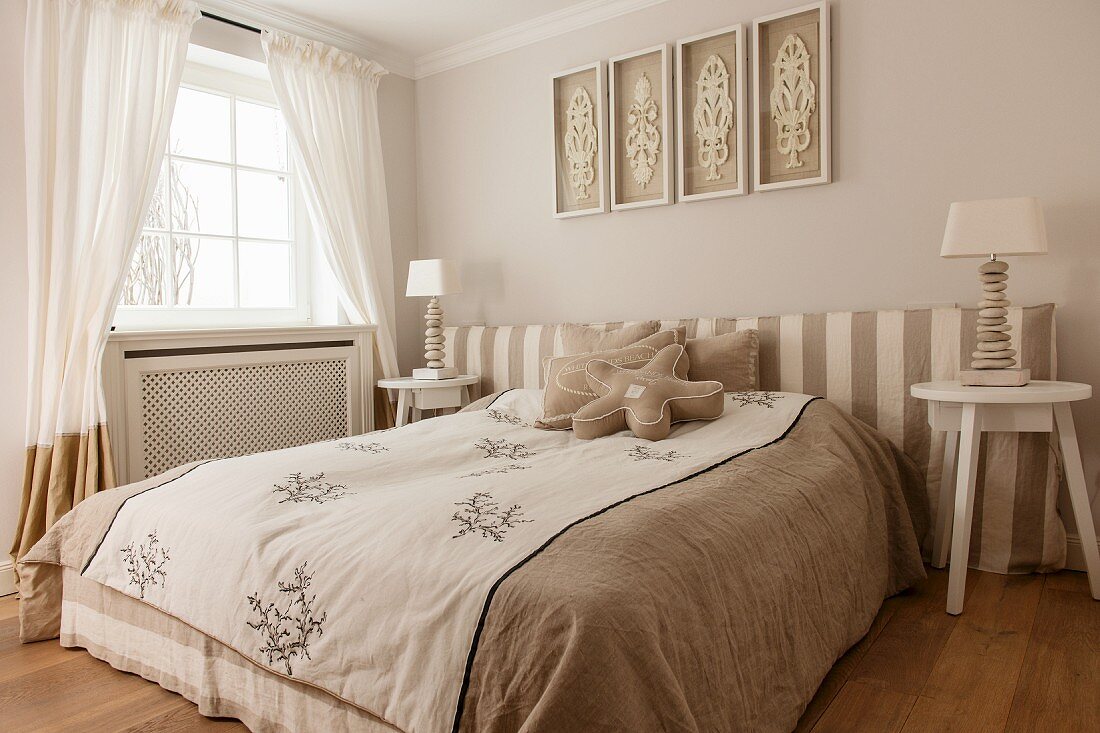 Doppelbett und an Wand Polsterkopfteil mit gestreiftem Bezug, Nachttische mit Tischleuchte im Schlafzimmer