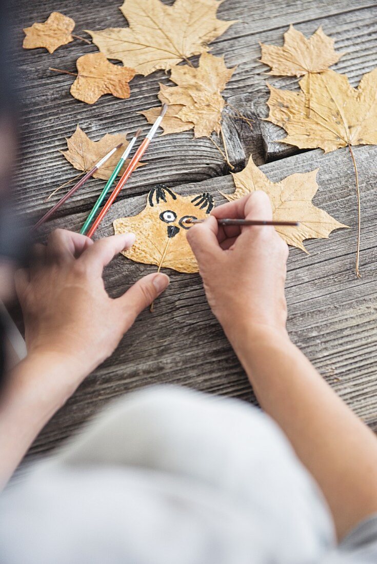 Painting an owl's face on a pressed autumn leaf