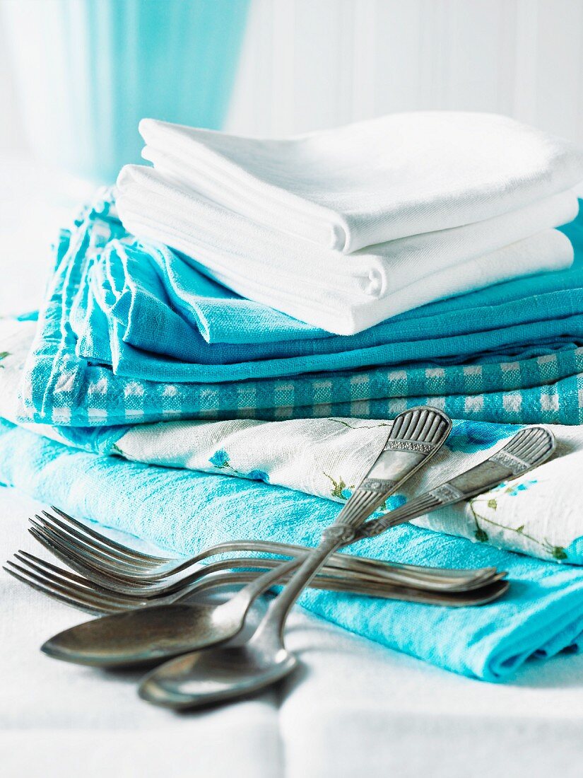Verschiedene blaue und weiße Tücher, gestapelt, mit Besteck