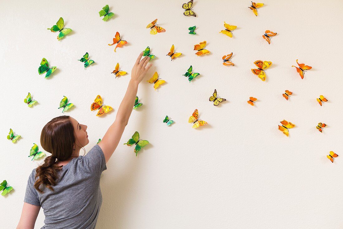 Woman decorating wall with butterflies