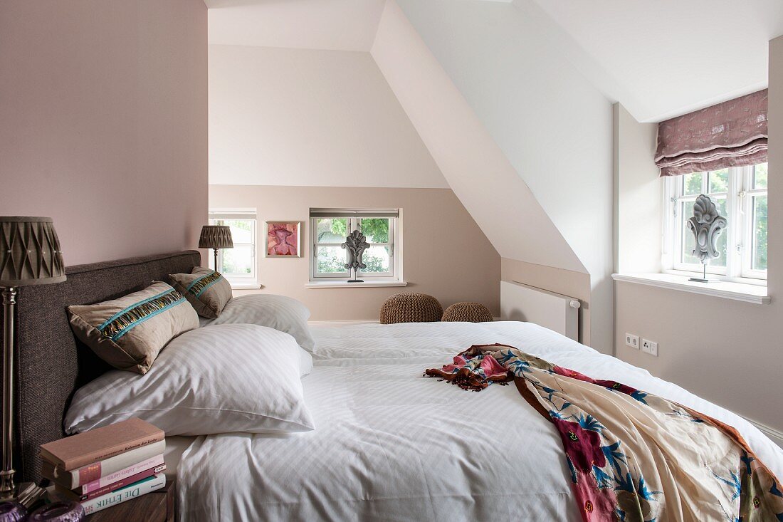 Schlafzimmer mit Doppelbett in ausgebautem Dachgeschoss, pastellfarben getönte Wände