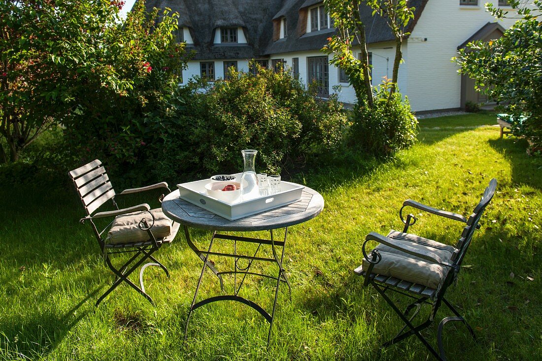 Sonniges Gartenplätzchen mit zwei Stühlen um rundem Tisch