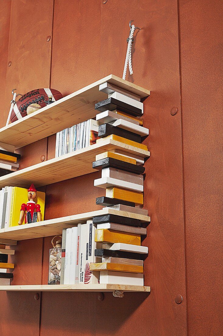 Hängendes Bücherregal aus farbigen Holzleisten